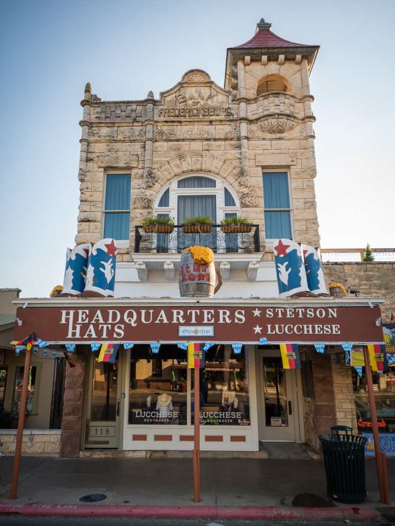 Historic stone building with Headquarters Hats store, decorated for Oktoberfest, at 118 address.